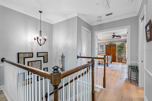 hall with ornamental molding, light wood-type flooring, and a notable chandelier