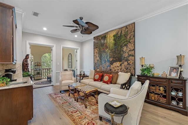 living room with sink, ceiling fan, light hardwood / wood-style floors, and crown molding