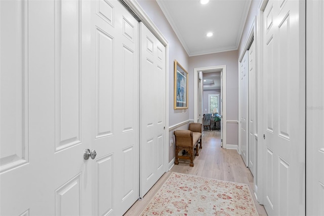 hall with light hardwood / wood-style floors and crown molding