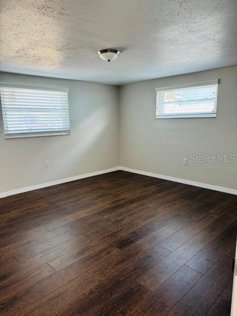 empty room featuring a textured ceiling and dark hardwood / wood-style flooring