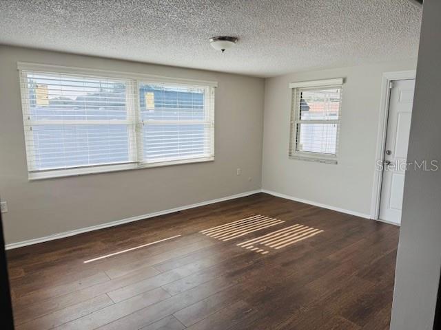 unfurnished room with dark hardwood / wood-style flooring, a wealth of natural light, and a textured ceiling