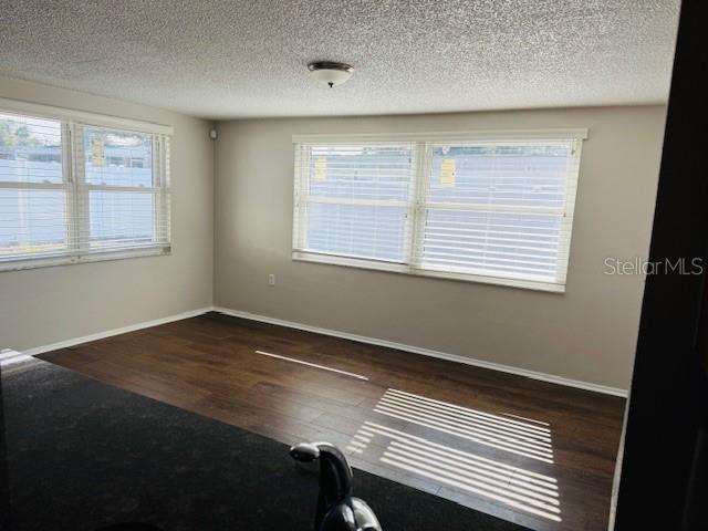 empty room with a textured ceiling and dark hardwood / wood-style floors