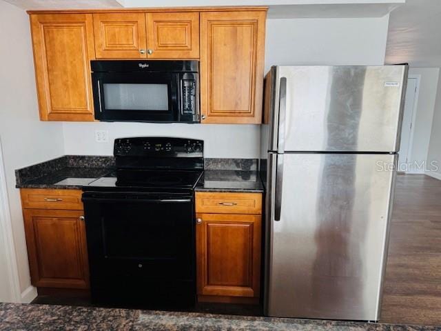 kitchen with black appliances, dark stone counters, and dark hardwood / wood-style floors