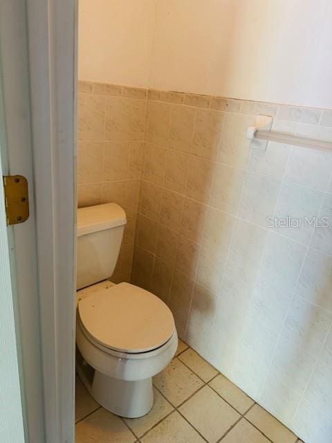 bathroom with toilet, tile walls, and tile patterned flooring