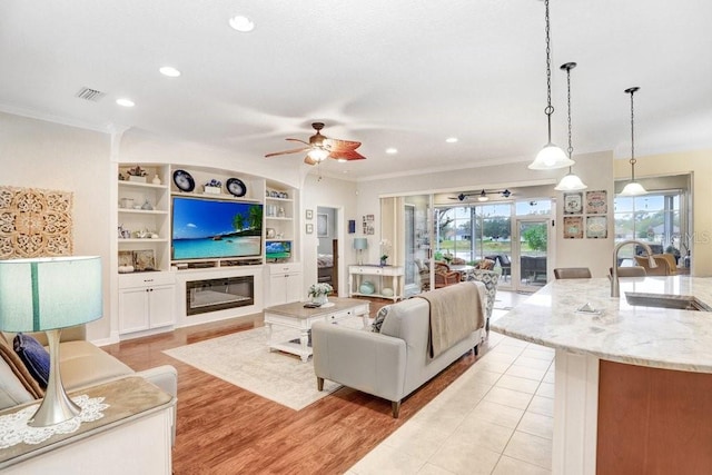 living room featuring sink, built in shelves, ornamental molding, and light tile patterned flooring