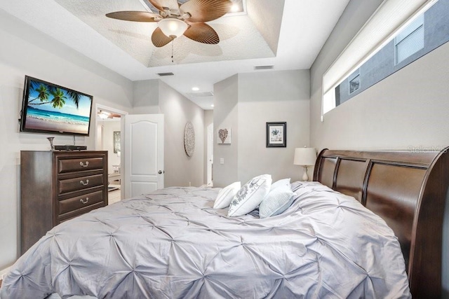 bedroom with ceiling fan and a raised ceiling