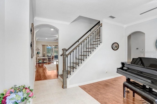 foyer entrance with ceiling fan, light tile patterned floors, and ornamental molding