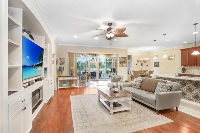 living room with ceiling fan, sink, light hardwood / wood-style flooring, and ornamental molding