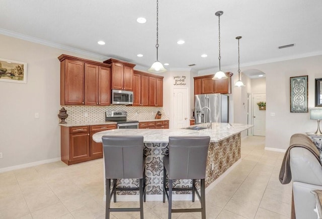 kitchen featuring pendant lighting, stainless steel appliances, a kitchen breakfast bar, sink, and a kitchen island with sink