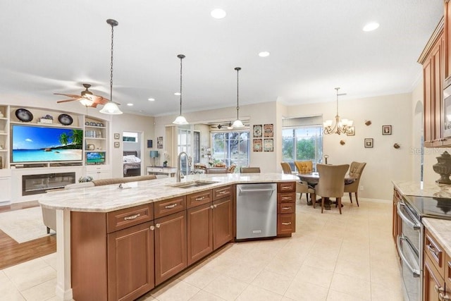 kitchen with pendant lighting, sink, a kitchen island with sink, appliances with stainless steel finishes, and ceiling fan with notable chandelier