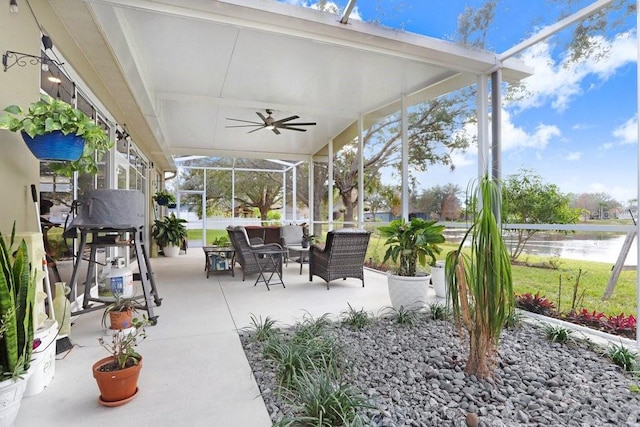 view of patio / terrace featuring a water view, ceiling fan, an outdoor living space, and glass enclosure