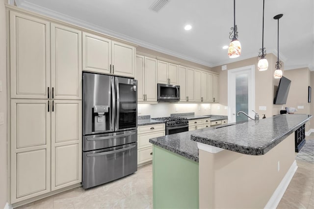 kitchen featuring a kitchen island with sink, cream cabinetry, appliances with stainless steel finishes, hanging light fixtures, and sink