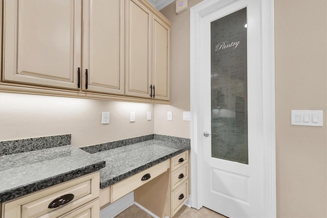 kitchen featuring built in desk, ornamental molding, and light tile patterned floors