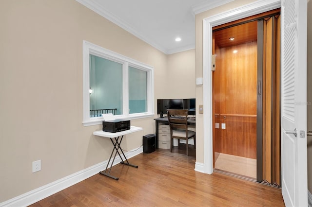 office space featuring elevator, ornamental molding, and light hardwood / wood-style flooring