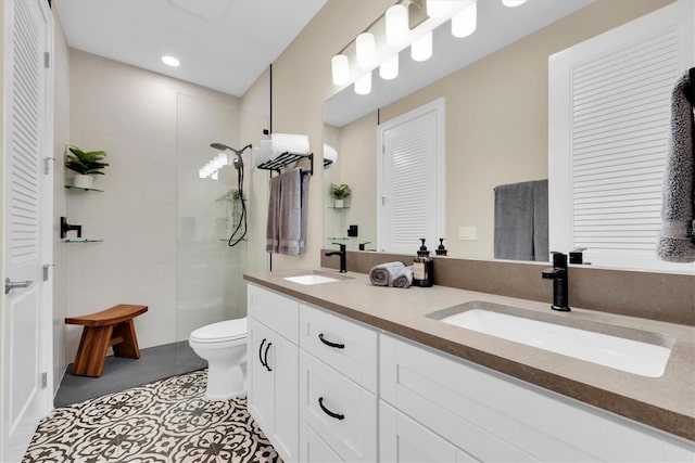 bathroom with tiled shower, tile patterned flooring, vanity, and toilet