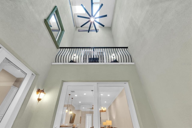 interior space featuring a high ceiling and ceiling fan with notable chandelier