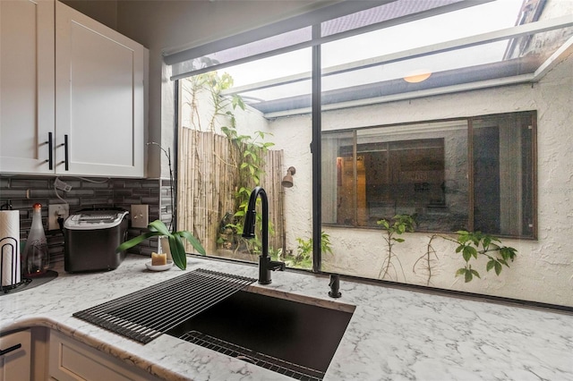 details featuring sink, white cabinets, and light stone countertops