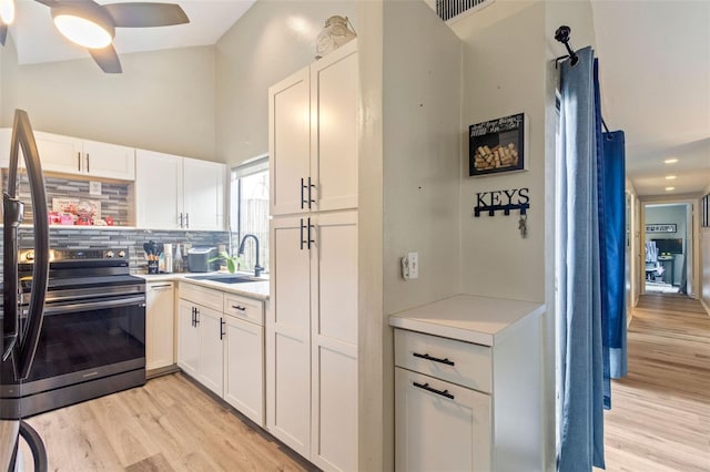 kitchen with range with electric stovetop, light wood-type flooring, sink, white cabinetry, and tasteful backsplash