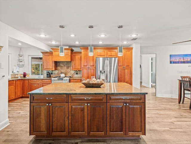 kitchen featuring stainless steel appliances, light stone counters, tasteful backsplash, a kitchen island, and pendant lighting