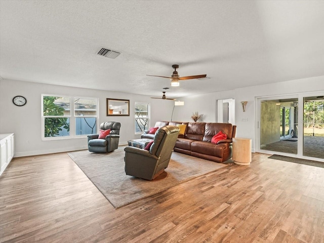 living room featuring a textured ceiling, ceiling fan, and light hardwood / wood-style floors