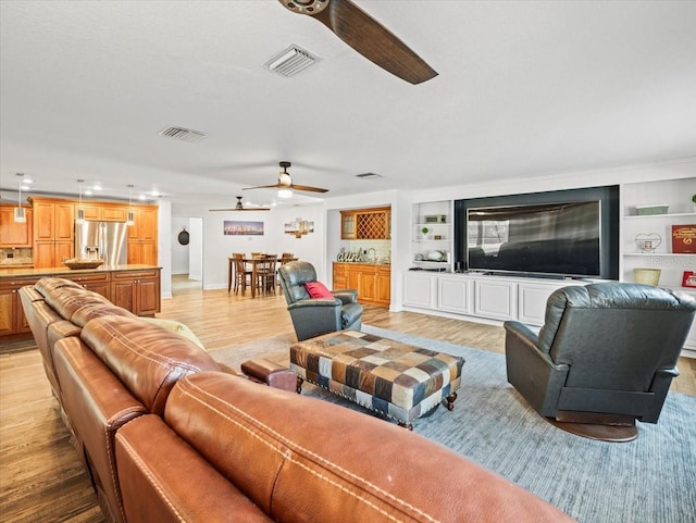 living room with built in shelves and light hardwood / wood-style flooring