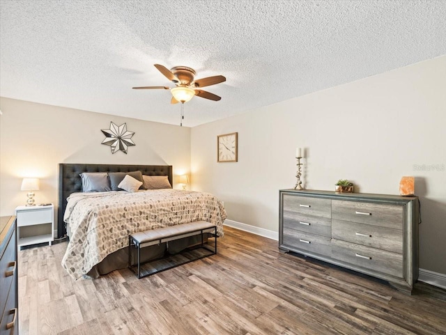 bedroom featuring ceiling fan, hardwood / wood-style floors, and a textured ceiling