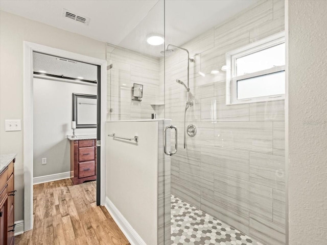 bathroom featuring hardwood / wood-style floors, a shower with door, and vanity