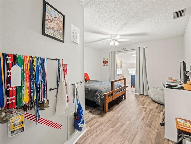 bedroom featuring a textured ceiling, ceiling fan, and light hardwood / wood-style flooring