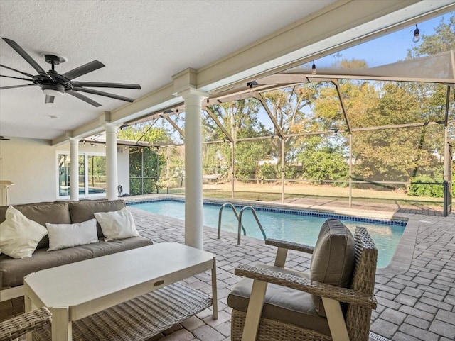 view of swimming pool with ceiling fan, glass enclosure, a patio area, and outdoor lounge area