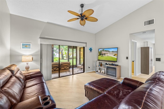 living room featuring vaulted ceiling, ceiling fan, a textured ceiling, and light hardwood / wood-style floors