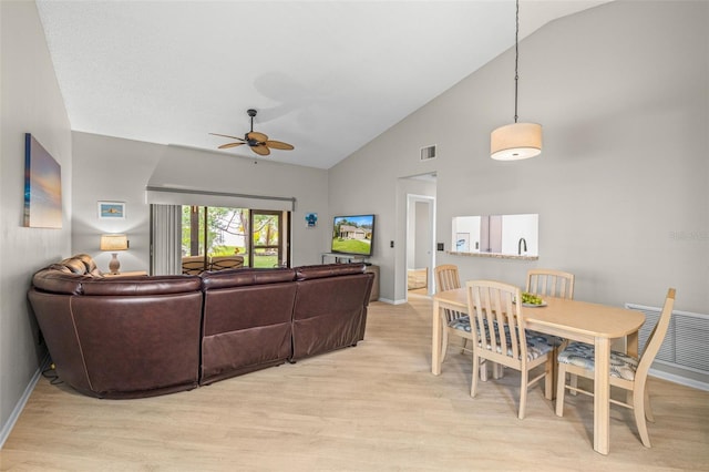 living room with ceiling fan, light hardwood / wood-style flooring, and vaulted ceiling