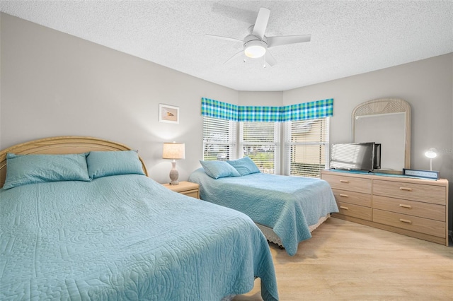 bedroom with a textured ceiling, ceiling fan, and light wood-type flooring