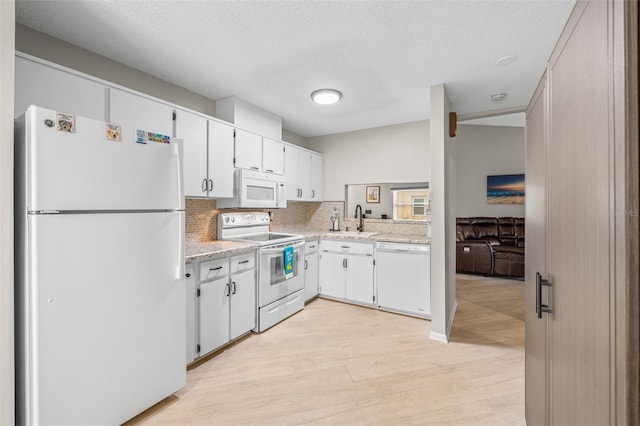 kitchen with white appliances, white cabinets, a textured ceiling, tasteful backsplash, and sink