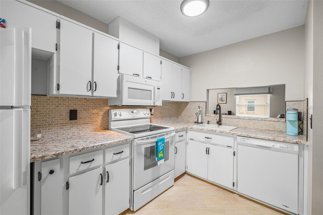 kitchen with a textured ceiling, sink, white cabinets, and white appliances