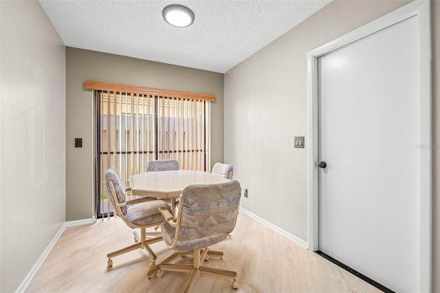 dining space with a textured ceiling and light wood-type flooring