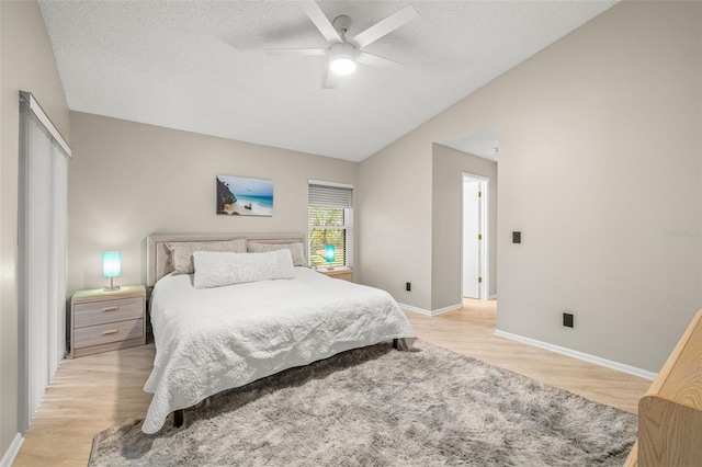 bedroom featuring ceiling fan, light wood-type flooring, a textured ceiling, and lofted ceiling