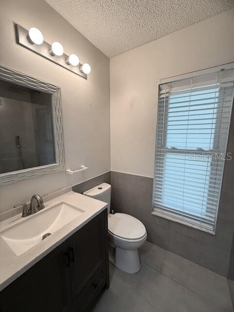 bathroom with toilet, vanity, tile patterned floors, and a textured ceiling