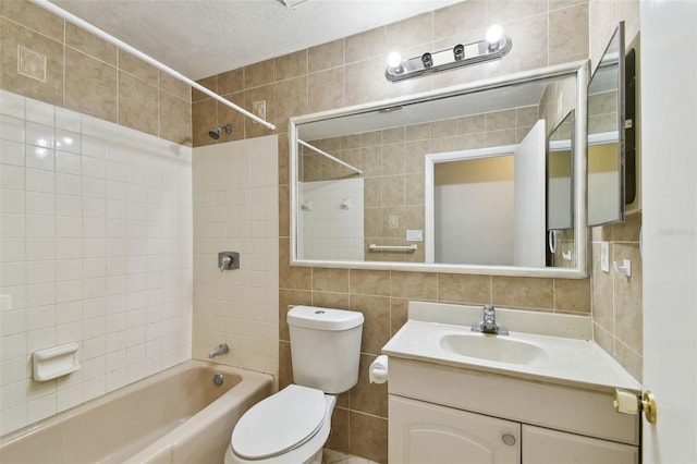 full bathroom featuring toilet, vanity, tile walls, a textured ceiling, and backsplash