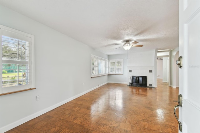 unfurnished living room featuring a brick fireplace, a textured ceiling, and ceiling fan