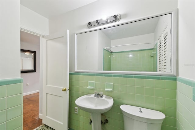 bathroom featuring toilet, a tile shower, and tile walls