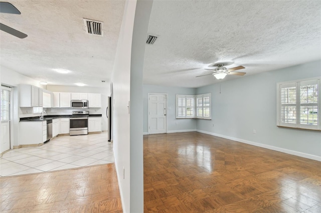 unfurnished living room featuring sink, ceiling fan, and a wealth of natural light