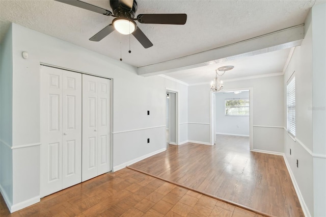 unfurnished bedroom with a textured ceiling, beamed ceiling, hardwood / wood-style flooring, ceiling fan with notable chandelier, and a closet