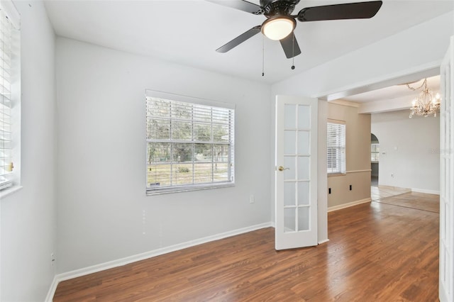 empty room with french doors, hardwood / wood-style floors, and ceiling fan with notable chandelier