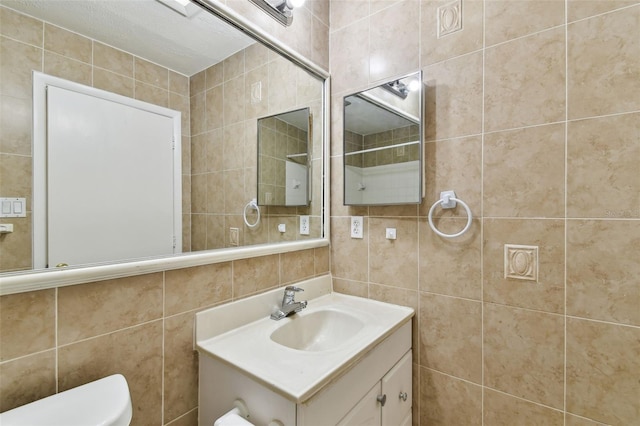 bathroom with toilet, tasteful backsplash, tile walls, and vanity