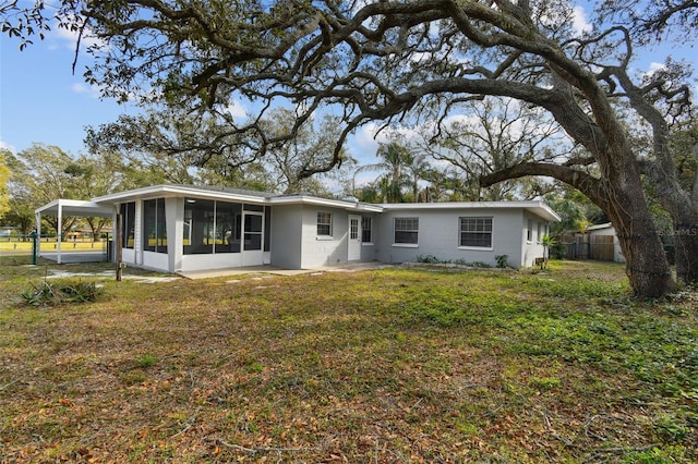 rear view of house featuring a carport, a lawn, and a sunroom