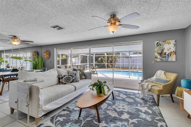 living room featuring light tile patterned flooring, ceiling fan, plenty of natural light, and a textured ceiling