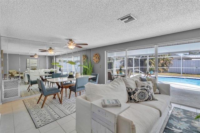 living room featuring light tile patterned floors, a textured ceiling, and ceiling fan