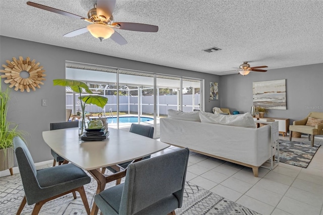 tiled dining area with ceiling fan and a textured ceiling