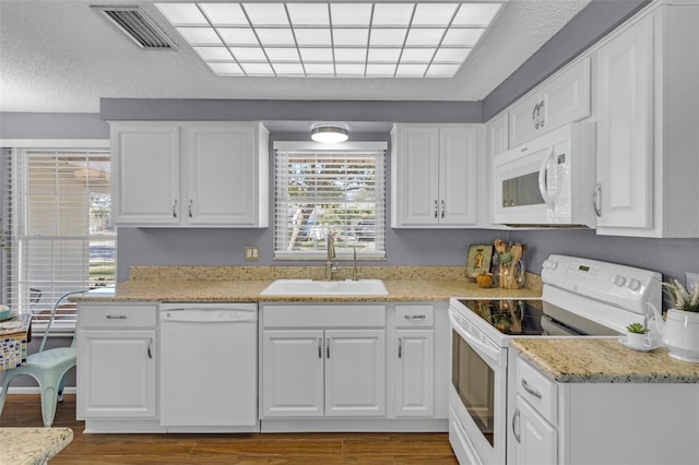 kitchen featuring sink, white cabinetry, light stone counters, hardwood / wood-style flooring, and white appliances