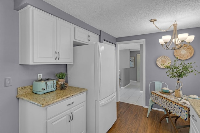 kitchen featuring white refrigerator, a notable chandelier, a textured ceiling, white cabinets, and dark hardwood / wood-style flooring